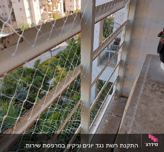 רשת מתכת מותקנת על מעקה למניעת כניסת יונים
